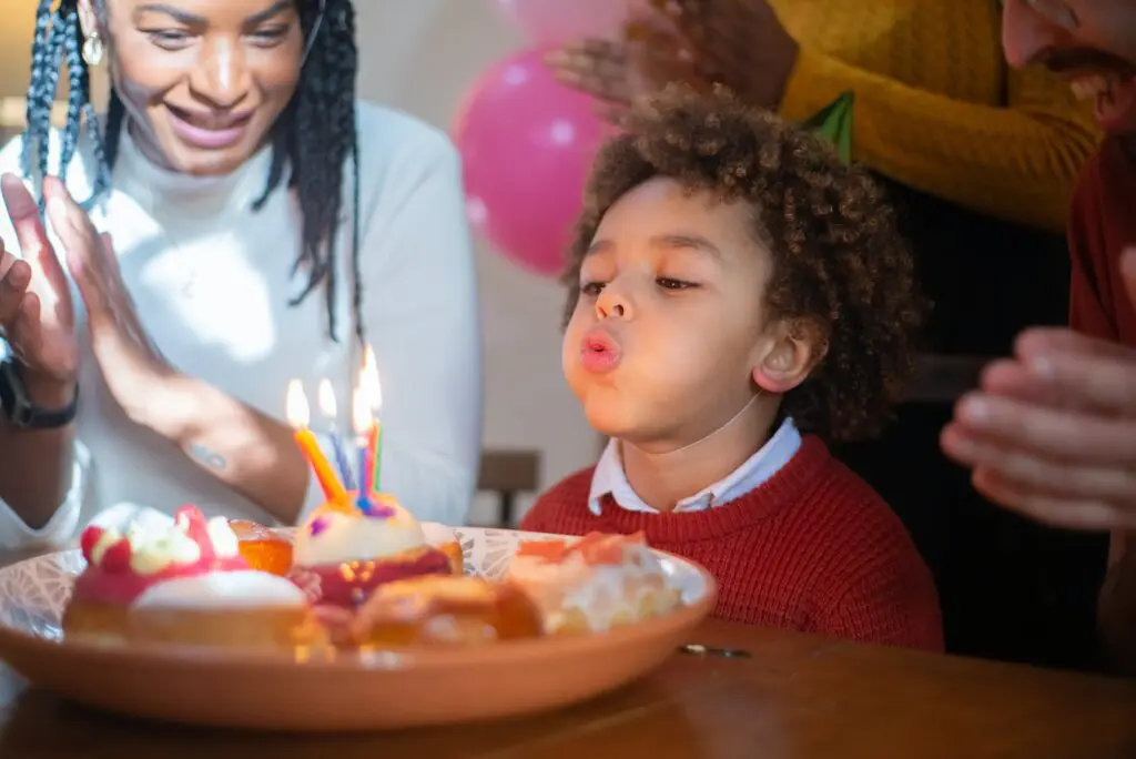 A child blowing out candles on his birthday cake.
